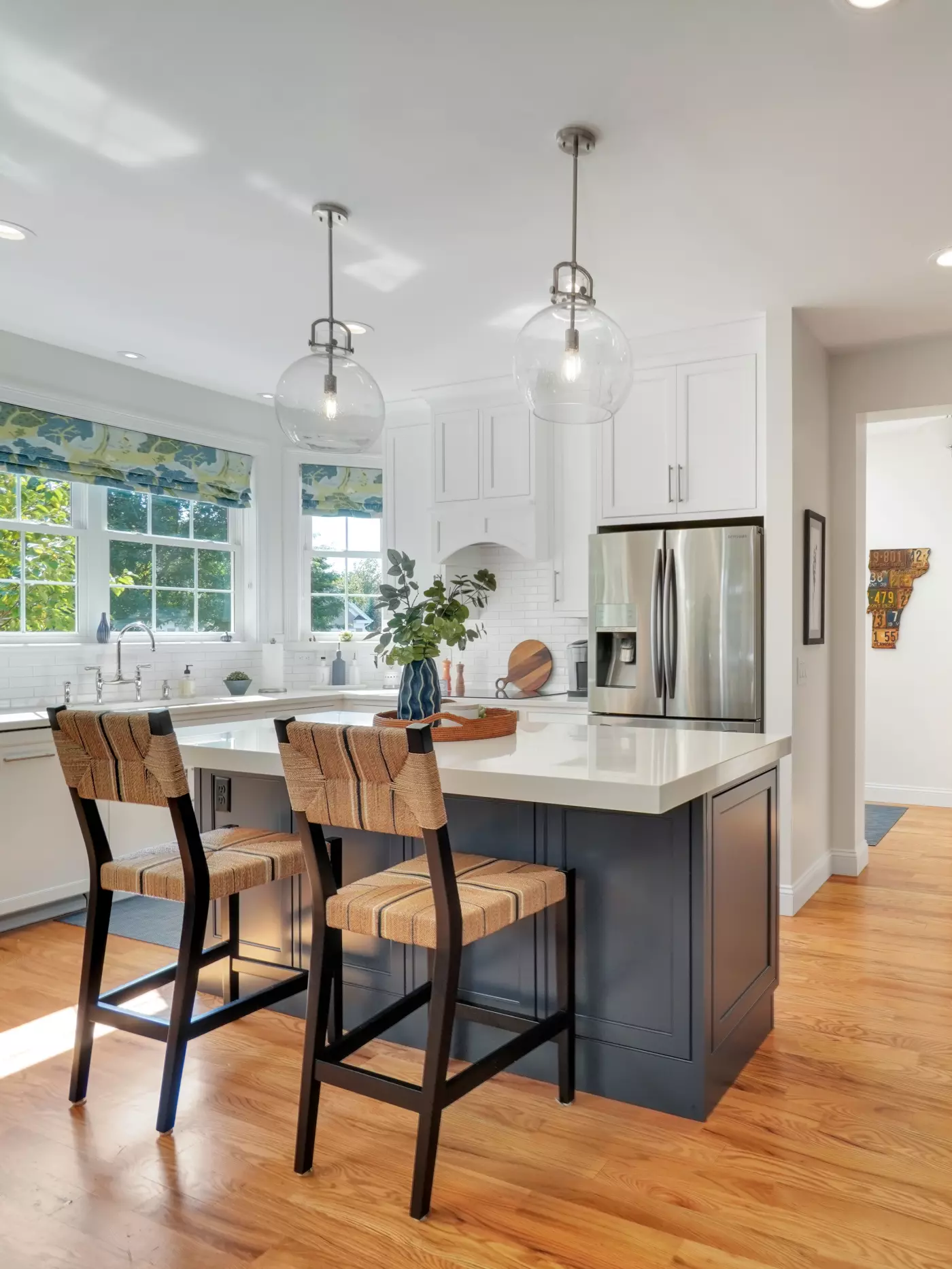 Modern kitchen with white cabinets, bar stools, and pendant lighting.