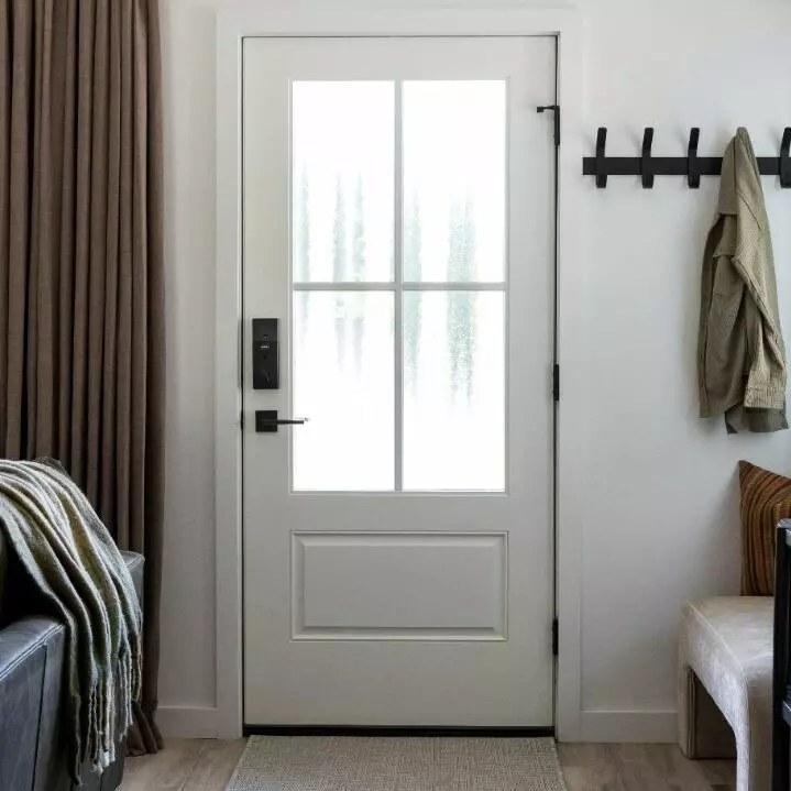 Bright entryway with a white door, coat hook, and soft furnishings.