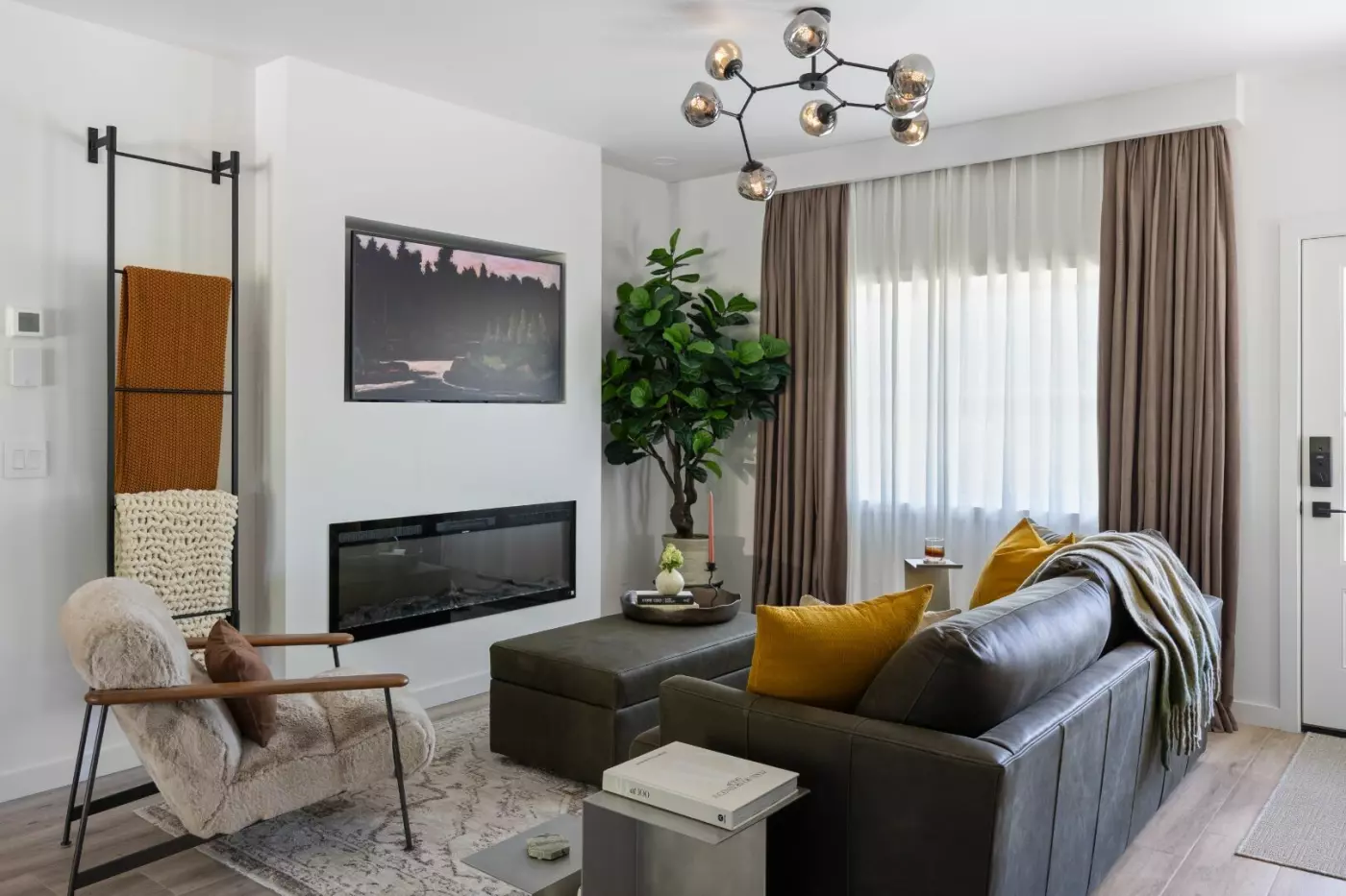 Cozy living room with a sofa, armchair, and decorative plants, featuring a modern fireplace.