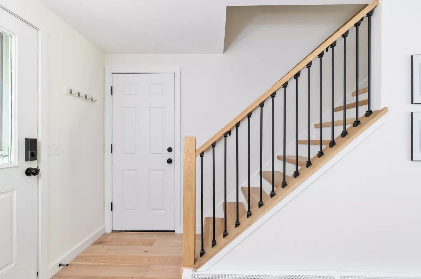 Bright entryway with a staircase, white walls, and wooden steps.
