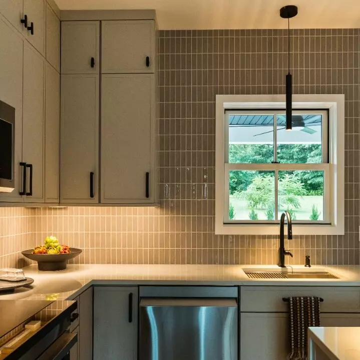 Modern kitchen with gray cabinetry, stainless appliances, and a window overlooking greenery.