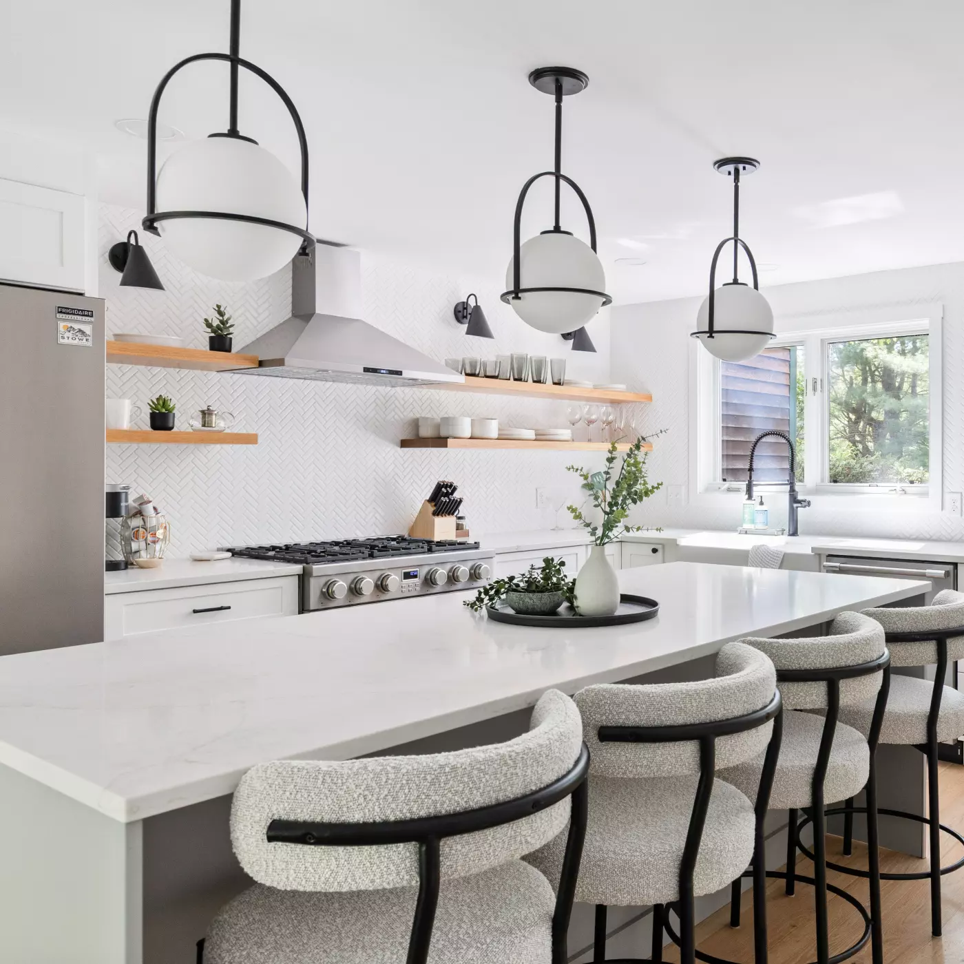 Modern kitchen with marble island, hanging lights, and open shelving.