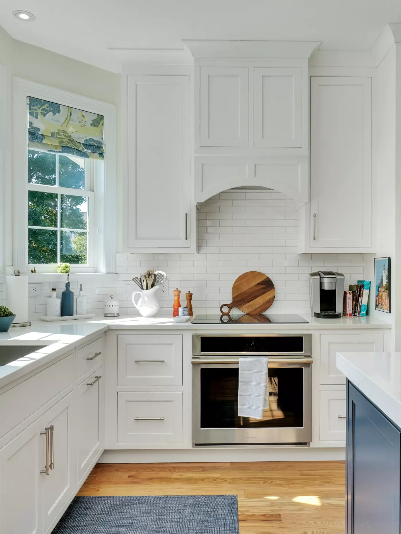 Modern kitchen with white cabinets, stainless steel oven, and a window view.