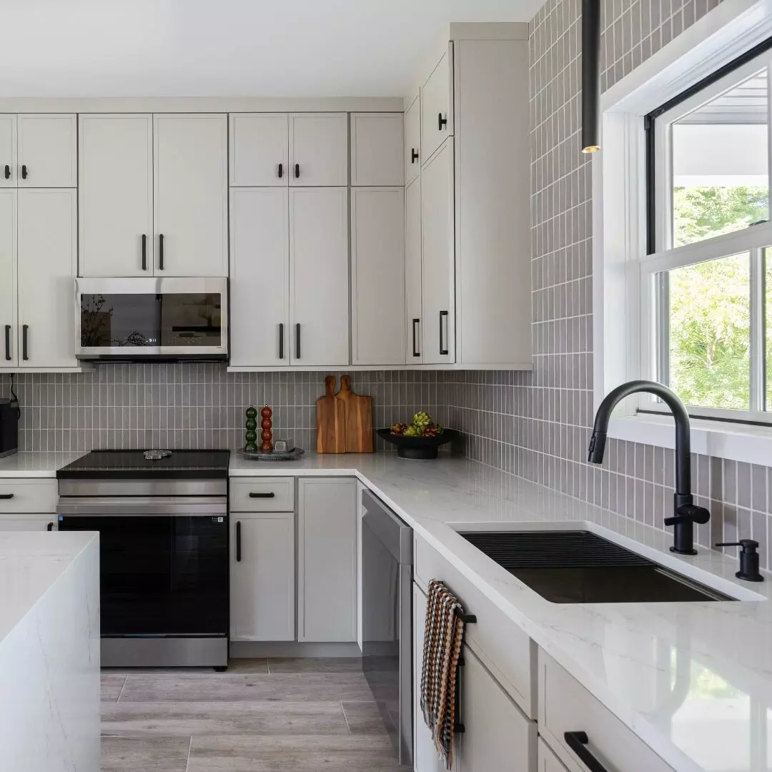 Modern kitchen with gray cabinets, stainless appliances, and a white countertop.