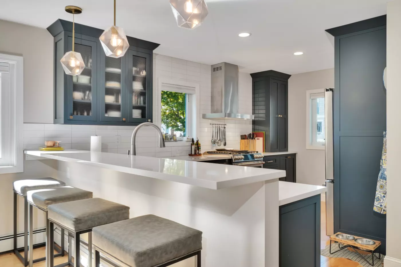 Modern kitchen with dark cabinets, white countertops, and elegant lighting fixtures.