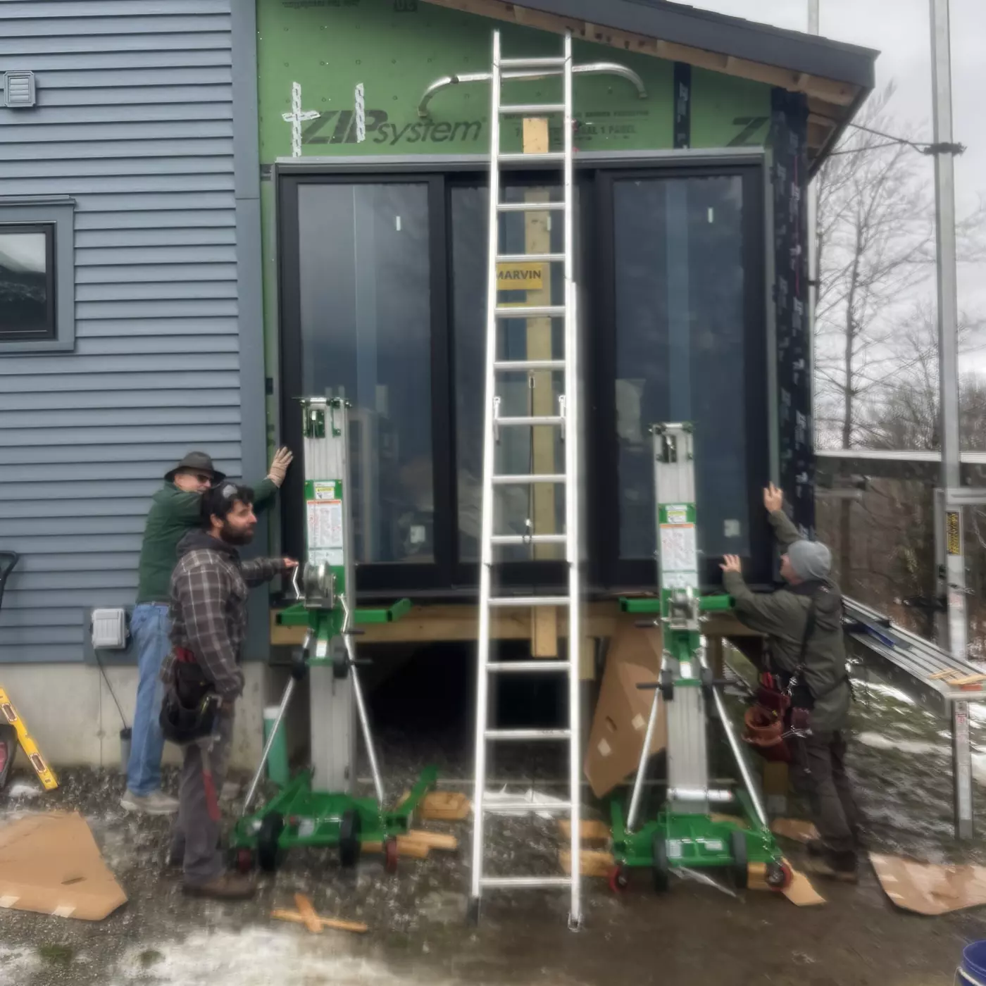 Workers installing large windows using lifts at a construction site.