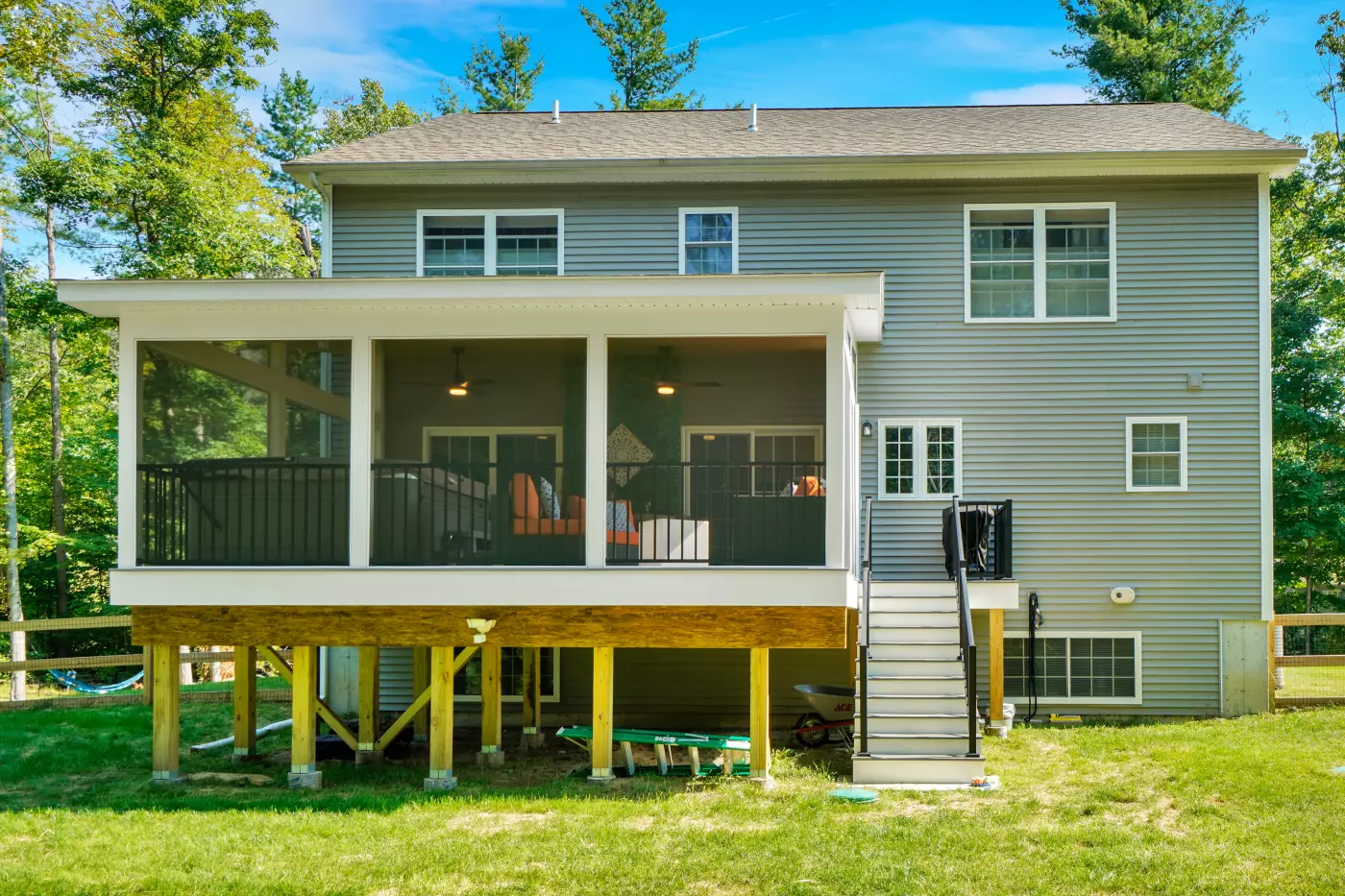 Modern two-story house with a screened porch, stairs, and green lawn.
