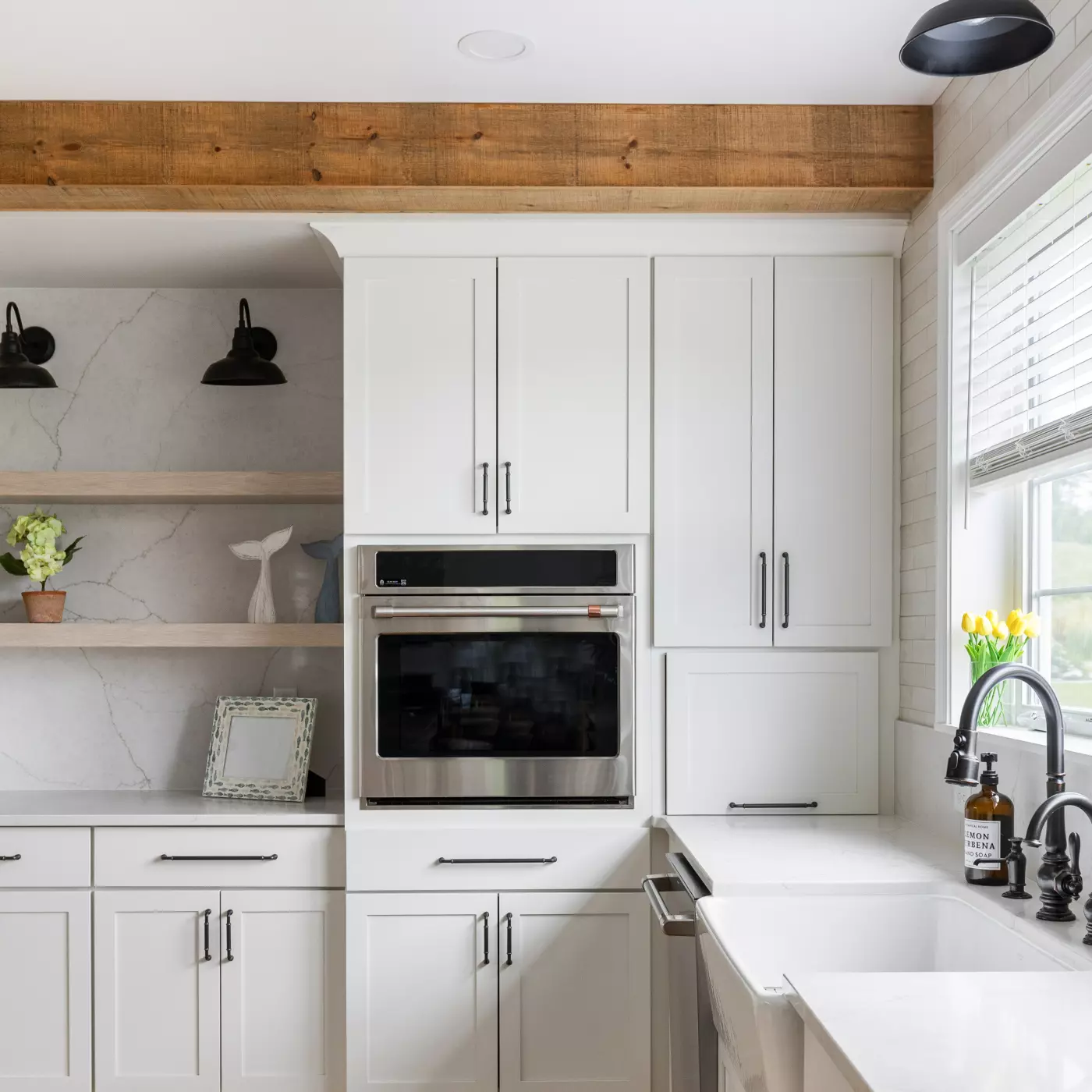 Modern kitchen with white cabinets, stainless steel appliances, and open wooden shelving.