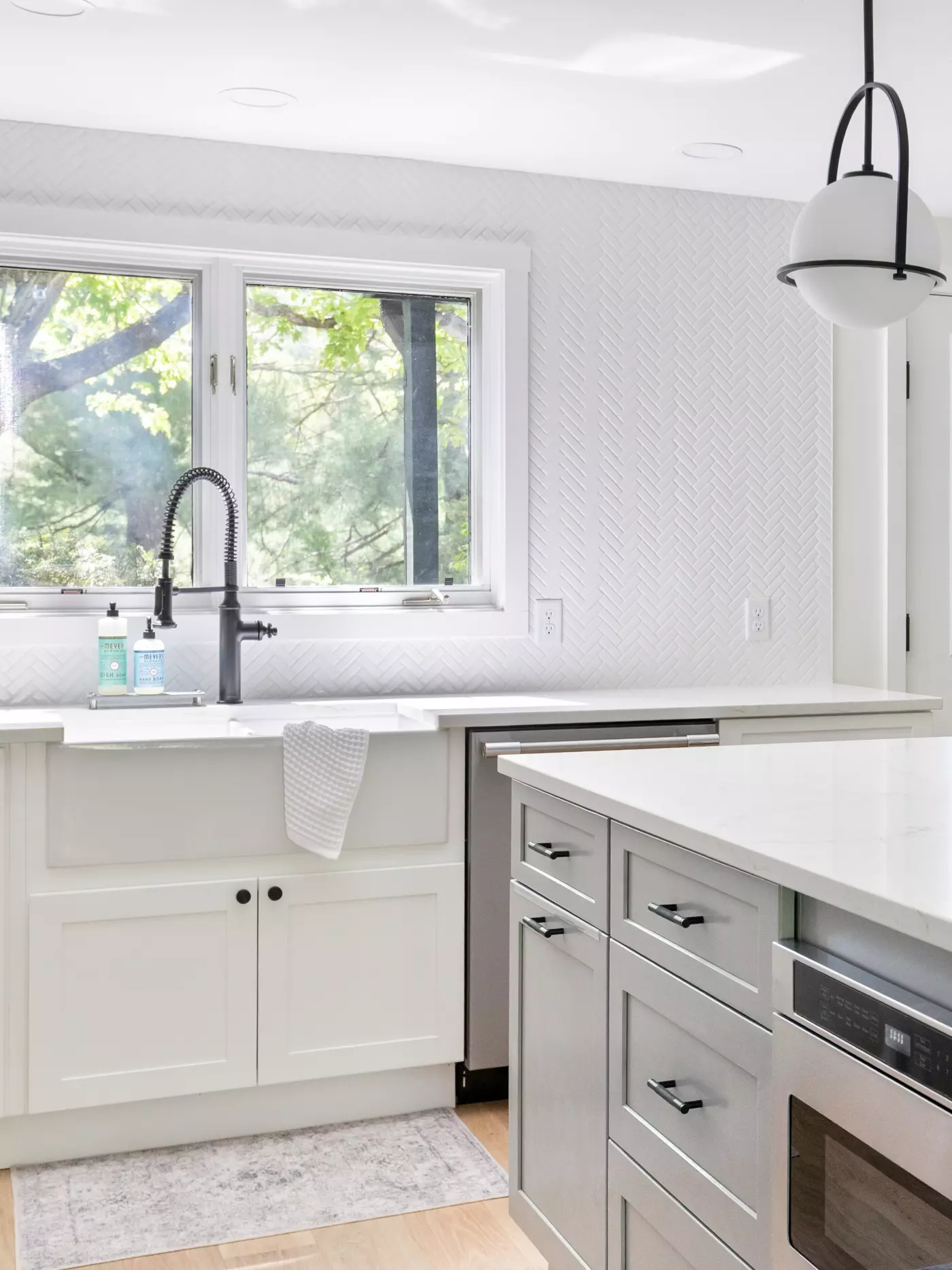 Bright kitchen featuring a farmhouse sink, herringbone wall, and modern cabinetry.