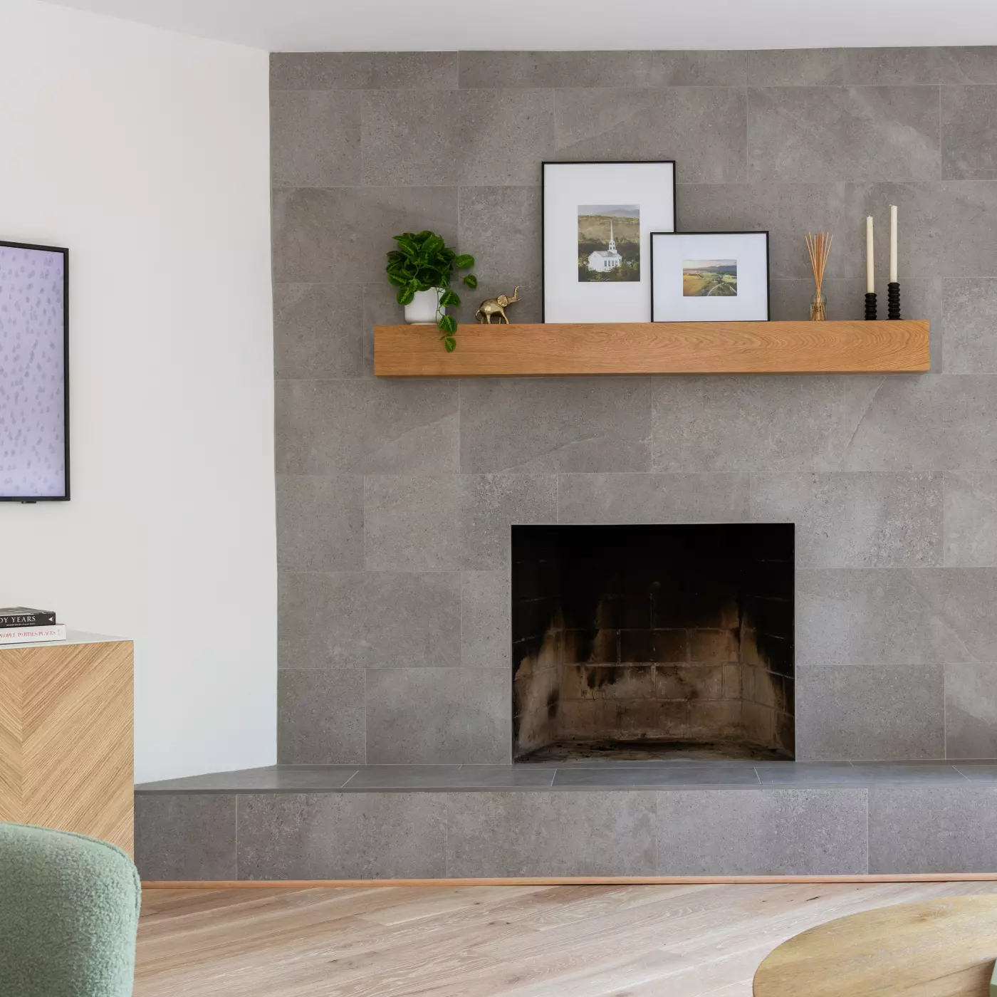Modern living room with a gray stone wall, wooden shelf, and a fireplace.
