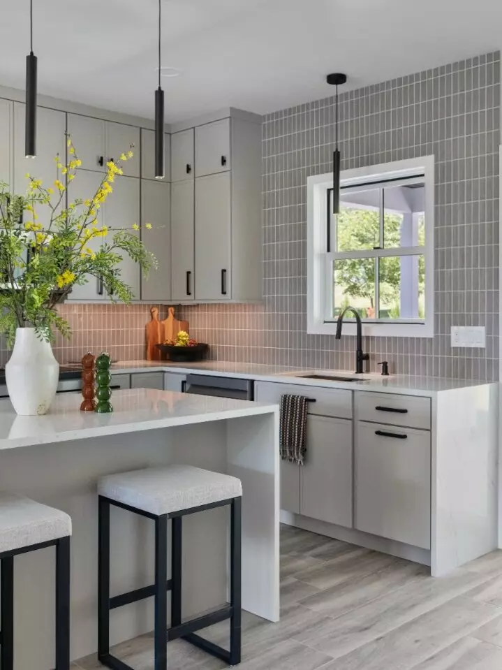 Modern kitchen with gray cabinets, a marble island, and pendant lights, adorned with flowers.