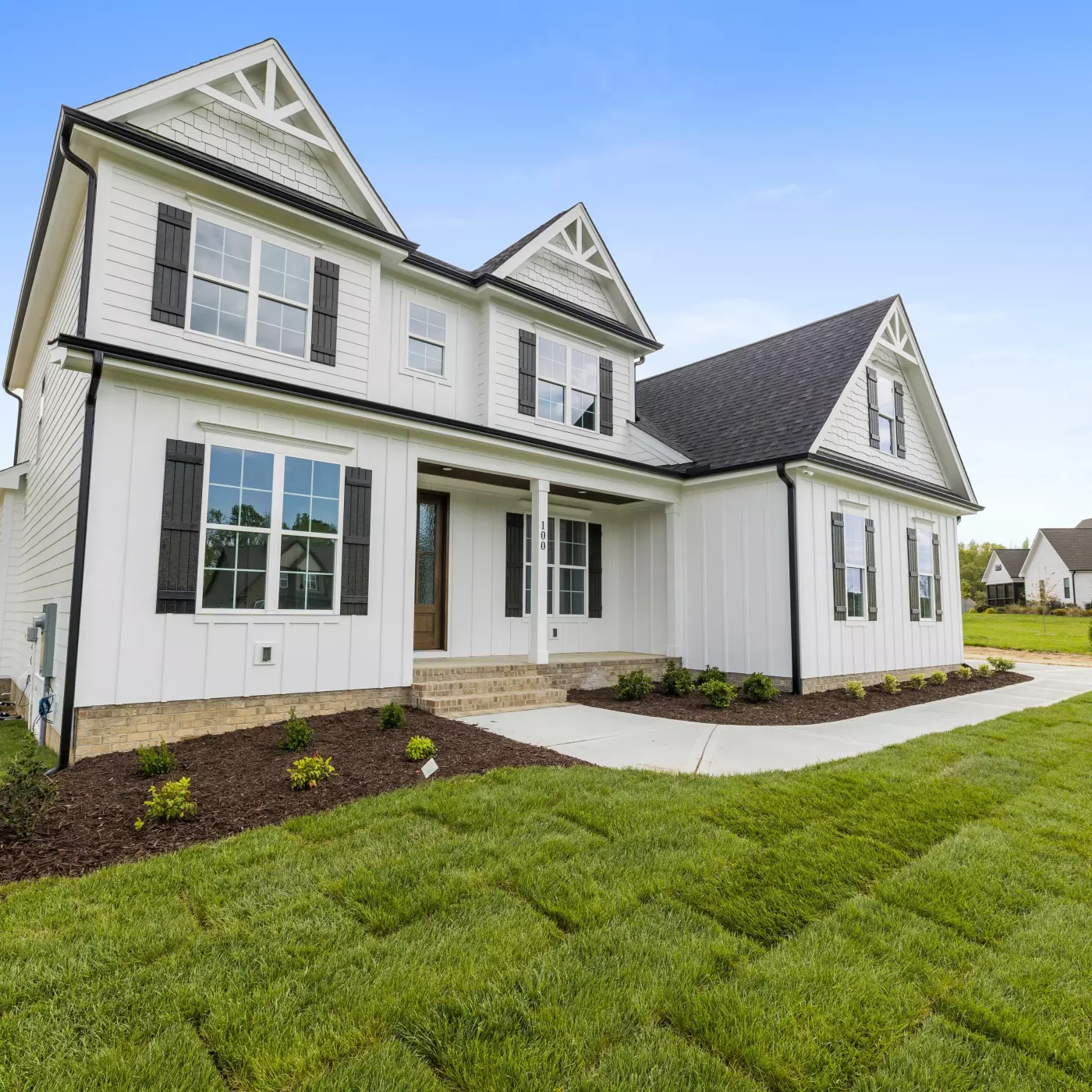 New two-story house with white siding, black shutters, and landscaped yard.