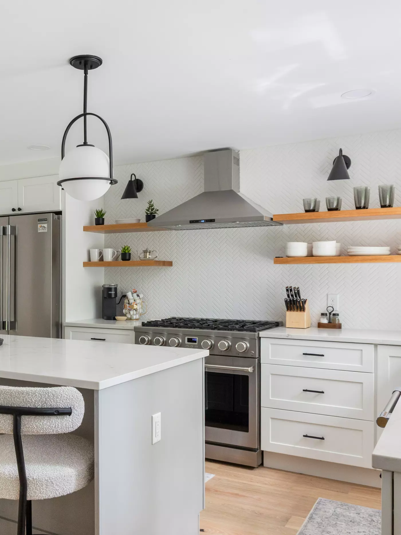 Modern kitchen featuring stainless steel appliances, open shelving, and stylish lighting.