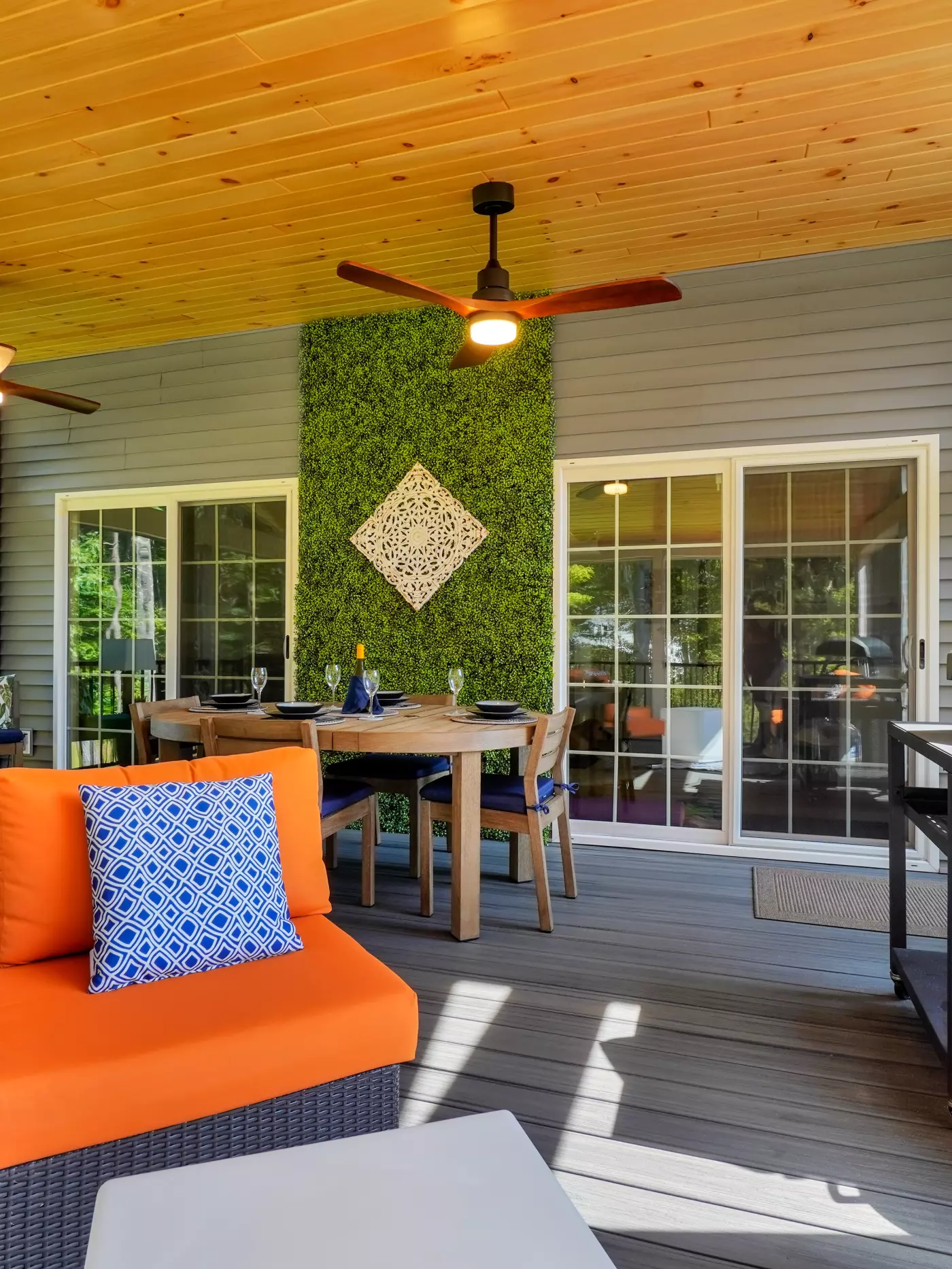 Cozy outdoor patio with orange seating, rustic dining area, and green decorative wall.