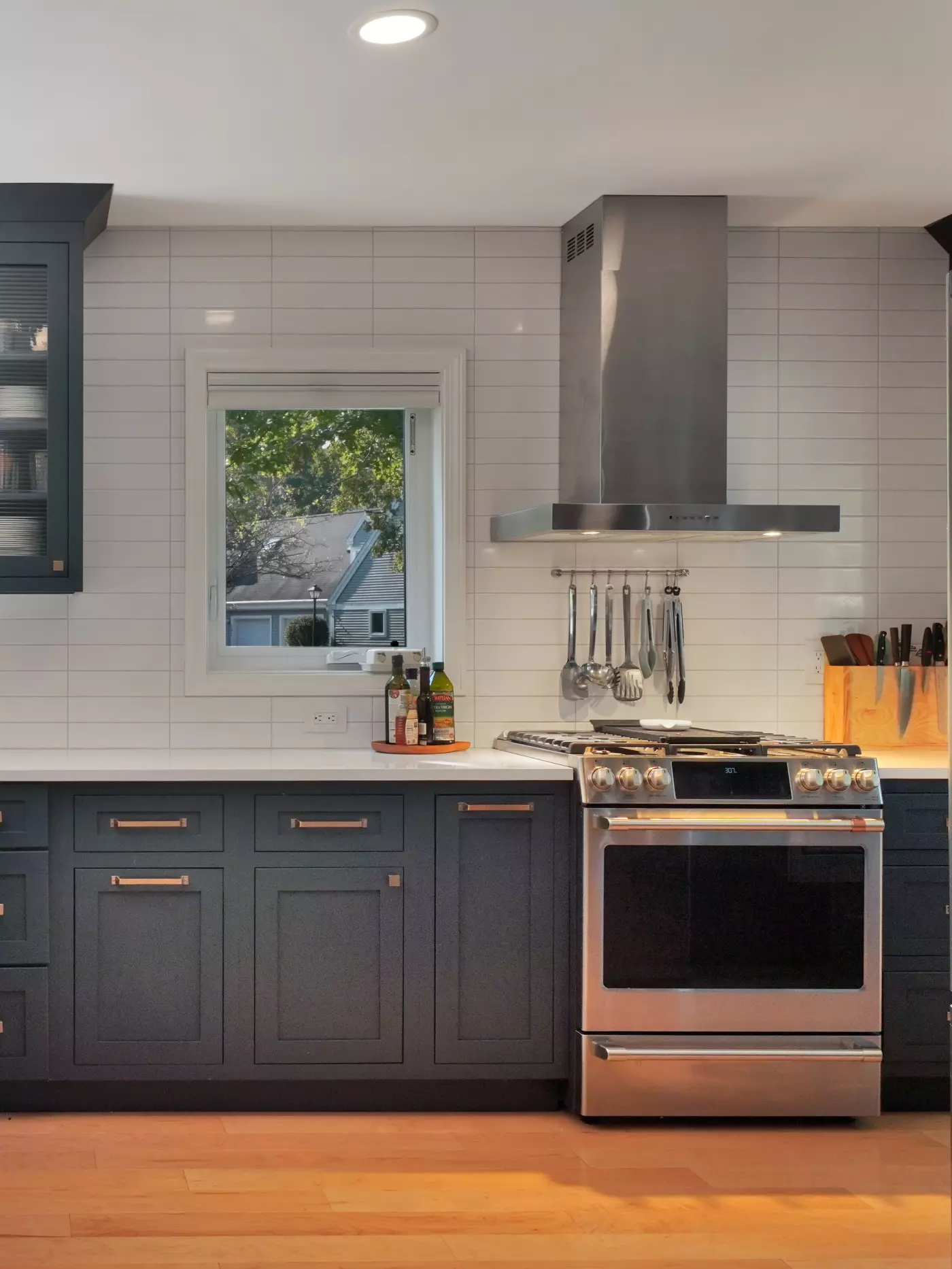 Modern kitchen with dark cabinets, stainless steel oven, and a window view.