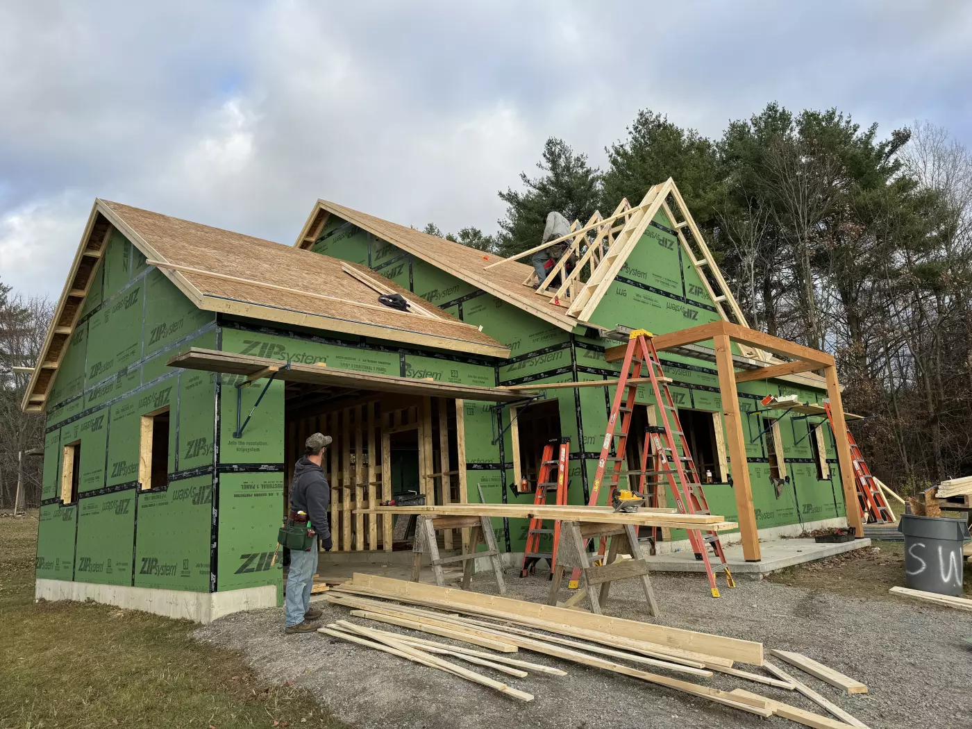 Construction of a house in progress with green sheathing and wooden framing.