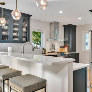 Modern kitchen with dark cabinetry, white countertops, and stylish lighting fixtures.