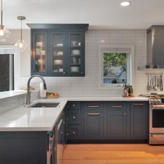 Modern kitchen with dark cabinets, stainless appliances, and natural light.
