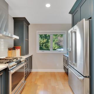 Modern kitchen with dark cabinets, stainless steel appliances, and a window view.