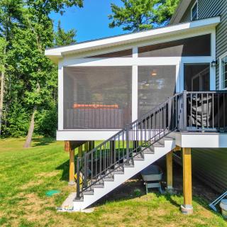 Screened porch with stairs leading down to a grassy yard, surrounded by trees.