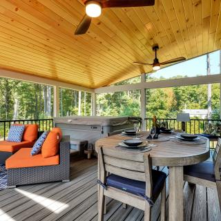 Cozy outdoor patio with seating, dining area, and hot tub, surrounded by greenery.
