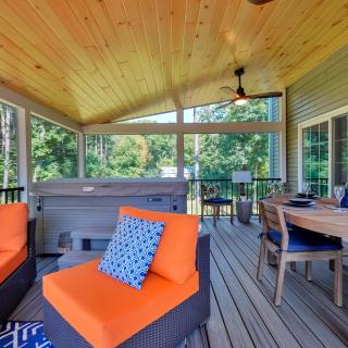 Stylish outdoor patio with seating, dining table, and a hot tub surrounded by greenery.