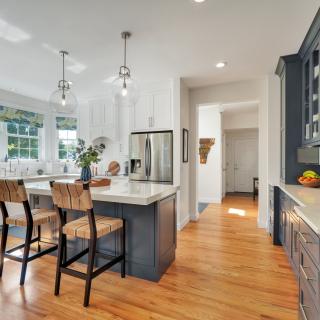 Modern kitchen with white and navy cabinets, island, and natural light.