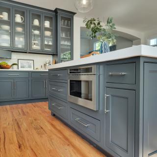 Modern kitchen with gray cabinetry, island, and stainless steel appliances. Bright and airy design.