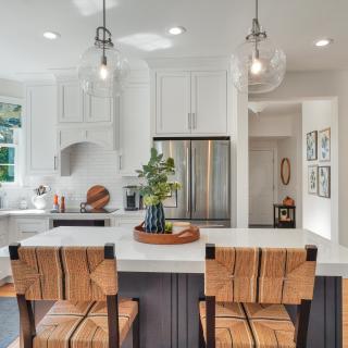 Bright kitchen featuring modern appliances, a marble island, and stylish bar stools.
