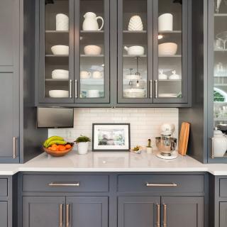 Modern kitchen with dark cabinetry, glass-front cabinets, and a countertop with decor items.
