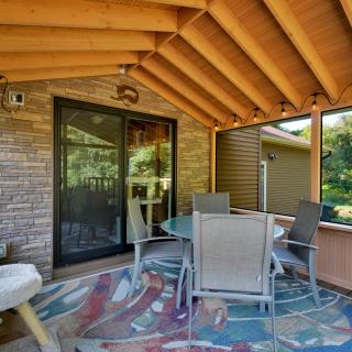 Cozy outdoor porch with a round table, chairs, and decorative lighting.