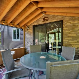 Screened porch with a round table, chairs, and string lights against wooden beams.