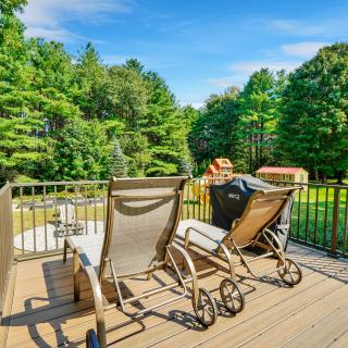 Sunny backyard deck with four reclining patio chairs overlooking a lush, tree-filled yard.