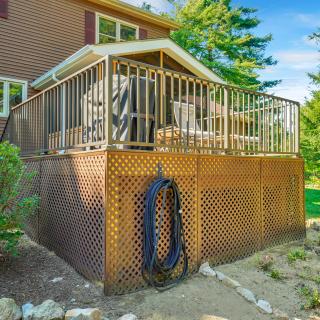 Raised wooden deck with white railings, lattice skirting, and a garden hose mounted below.