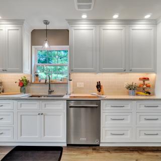 Modern kitchen with white cabinets, stainless appliances, and window view.