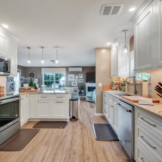 Modern kitchen with white cabinets, stainless steel appliances, and a cozy living area view.
