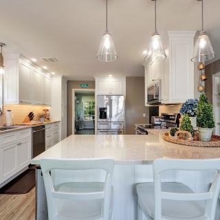 Modern kitchen with white cabinets, a marble countertop, and stylish pendant lighting.
