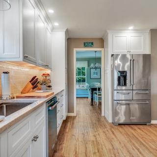 Bright kitchen with modern appliances, wood flooring, and a view into a dining area.