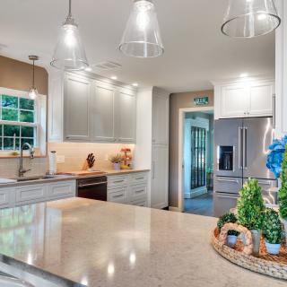 Bright, modern kitchen with gray cabinets, island, and flowers in vases.