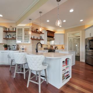Modern kitchen featuring white cabinets, a large island, and stylish pendant lights.