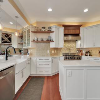 Modern kitchen with white cabinets, island, and stylish backsplash.