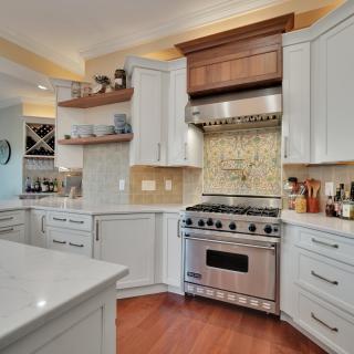 Bright modern kitchen with white cabinets, stainless steel appliances, and decorative tile backsplash.