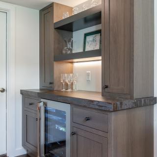 Modern wooden bar area with glassware and a wine cooler.