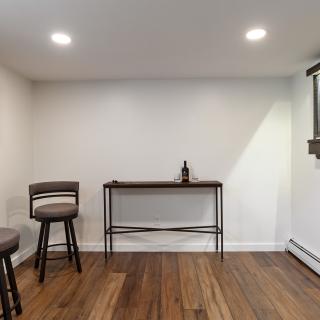 A cozy game room with dartboard, a table, and two barstools.