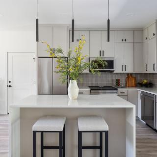 Modern kitchen with gray cabinets, a large island, and a vase of flowers centerpiece.