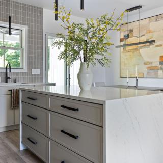 Modern kitchen with an island, decorative flowers, and abstract wall art.