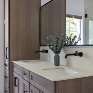 Modern bathroom with double sink, wooden cabinetry, and a mirror above.