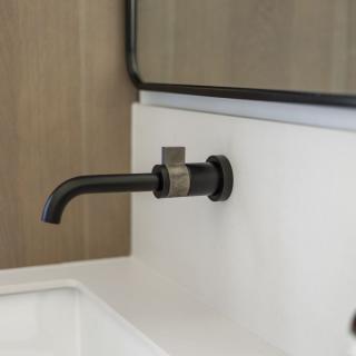 Modern black faucet mounted on a white countertop with a mirror in the background.