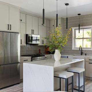Modern kitchen with gray cabinets, stainless steel appliances, and a marble island centerpiece.