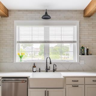 Bright kitchen with a farmhouse sink, white cabinetry, and a view of greenery outside.